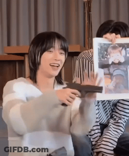 A Man In A Striped Sweater Is Holding A Picture Of A Child And Smiling . GIF