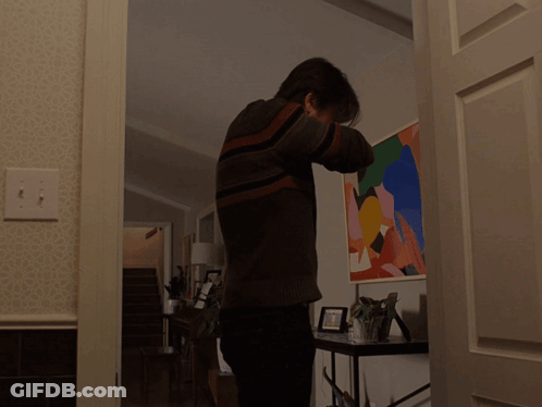 A Man In A Striped Sweater Is Standing In Front Of A Painting GIF