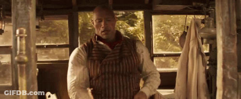 A Man In A Striped Vest Is Standing In A Room With A Window . GIF