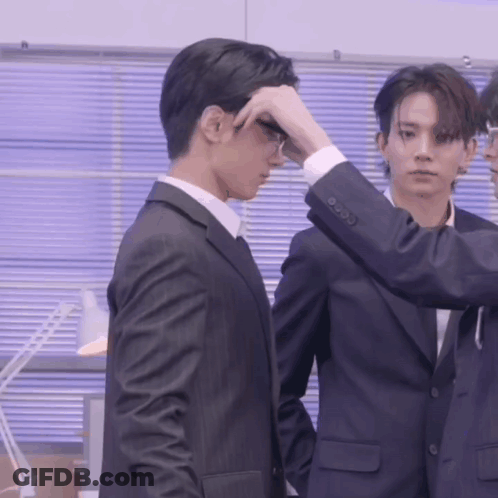 A Man In A Suit Adjusts His Glasses While Another Man Looks On GIF