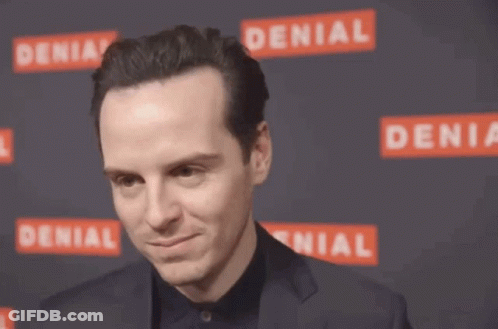 A Man In A Suit Adjusts His Hair In Front Of A Denial Sign GIF