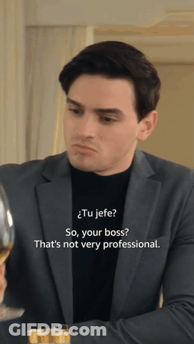 A Man In A Suit And A Black Turtleneck Is Talking To Another Man GIF