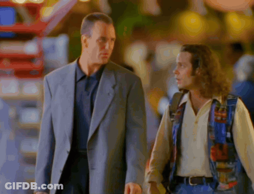 A Man In A Suit And A Man In A Colorful Vest Are Walking Down The Street GIF