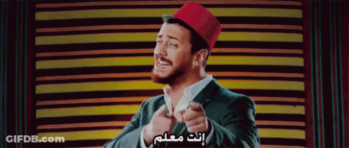 A Man In A Suit And A Red Hat Is Pointing At The Camera GIF