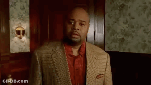A Man In A Suit And A Red Shirt Is Standing In A Room . GIF