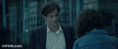 A Man In A Suit And A Woman In A Denim Jacket Are Talking To Each Other GIF