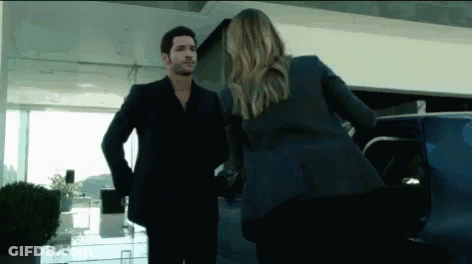 A Man In A Suit And A Woman In A Suit Are Standing Next To Each Other In Front Of A Car . GIF
