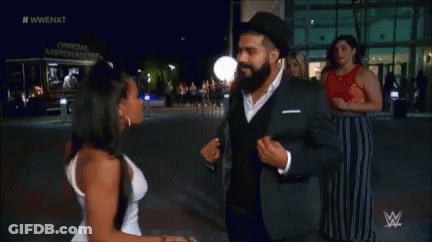 A Man In A Suit And A Woman In A White Dress Are Dancing Together . GIF