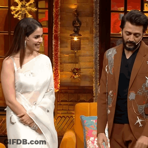 A Man In A Suit And A Woman In A White Saree Are Standing Next To Each Other GIF