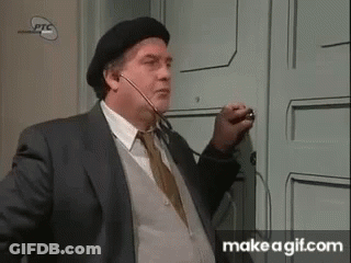 A Man In A Suit And Beret Is Standing In Front Of A Door . GIF