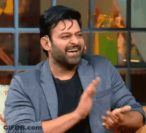 A Man In A Suit And Black Shirt Is Clapping His Hands And Smiling . GIF