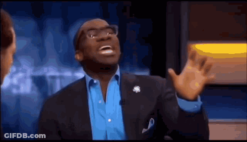 A Man In A Suit And Blue Shirt Is Making A Funny Face While Talking On A Television Show . GIF