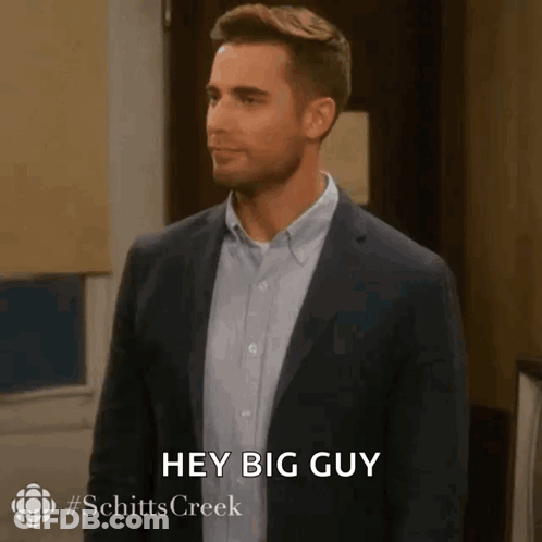 A Man In A Suit And Blue Shirt Is Saying Hey Big Guy . GIF