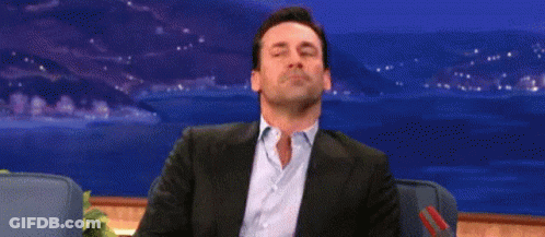 A Man In A Suit And Blue Shirt Is Sitting With His Eyes Closed . GIF