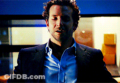 A Man In A Suit And Blue Shirt Is Standing In A Room GIF