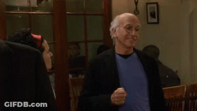 A Man In A Suit And Blue Shirt Is Standing Next To A Woman In A Room And Smiling . GIF
