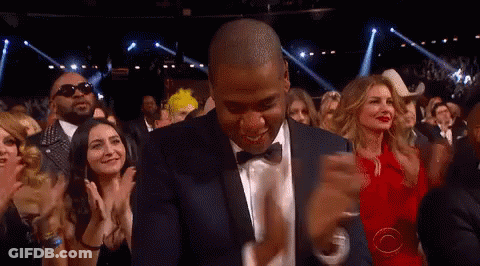 A Man In A Suit And Bow Tie Is Dancing In Front Of A Crowd Of People GIF