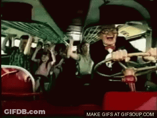 A Man In A Suit And Bow Tie Is Driving A Bus With A Crowd Of People . GIF
