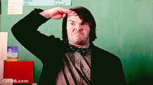A Man In A Suit And Bow Tie Is Making A Funny Face In Front Of A Chalkboard . GIF