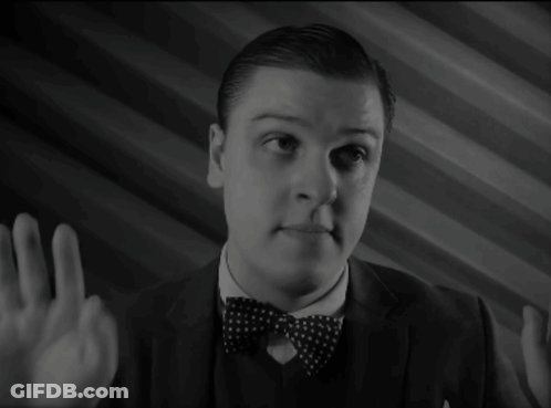 A Man In A Suit And Bow Tie Is Pointing GIF