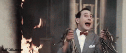 A Man In A Suit And Bow Tie Is Running In Front Of A Fire . GIF