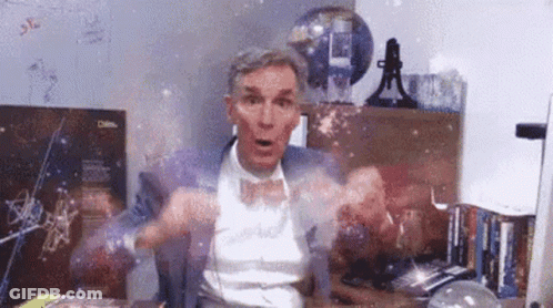 A Man In A Suit And Bow Tie Is Sitting At A Desk In Front Of A Computer . GIF