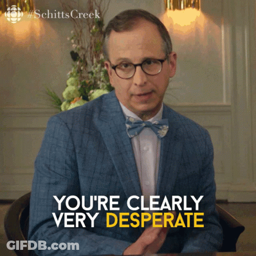 A Man In A Suit And Bow Tie Is Sitting At A Table And Says " You 'Re Clearly Very Desperate " GIF