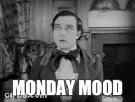 A Man In A Suit And Bow Tie Is Sitting In Front Of A Fireplace With The Words Monday Mood Above Him GIF