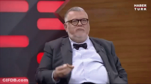 A Man In A Suit And Bow Tie Is Sitting In Front Of A Screen That Says Haber Turk . GIF