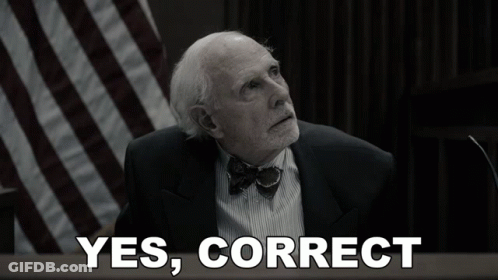 A Man In A Suit And Bow Tie Is Sitting In Front Of A Sign That Says Yes Correct GIF