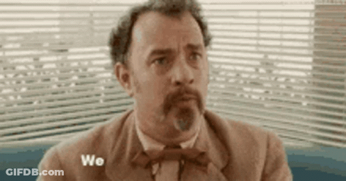 A Man In A Suit And Bow Tie Is Sitting In Front Of A Window With The Word We Written On It . GIF