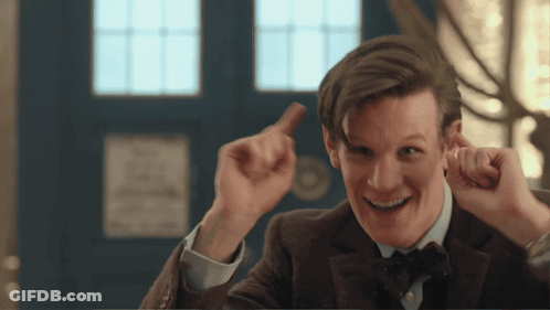 A Man In A Suit And Bow Tie Is Smiling And Holding Something In His Hand GIF