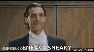 A Man In A Suit And Bow Tie Is Smiling And Says Sneaky Sneaky . GIF