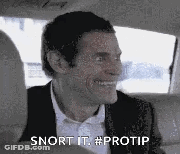 A Man In A Suit And Bow Tie Is Smiling In The Back Seat Of A Car . GIF