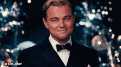 A Man In A Suit And Bow Tie Is Smiling GIF
