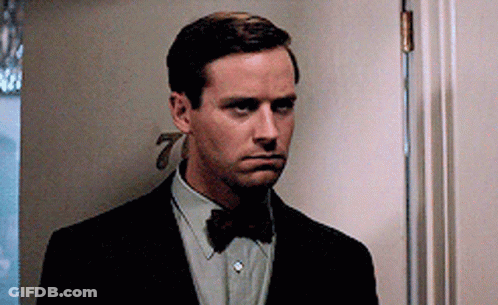 A Man In A Suit And Bow Tie Is Standing In A Doorway GIF