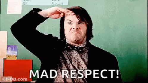 A Man In A Suit And Bow Tie Is Standing In Front Of A Blackboard And Making A Funny Face . GIF