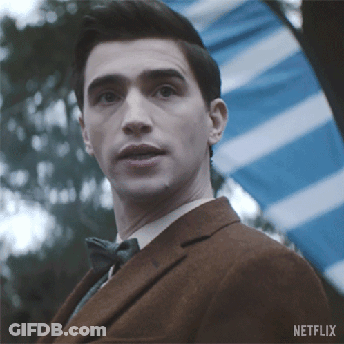 A Man In A Suit And Bow Tie Is Standing In Front Of A Blue And White Striped Flag And A Netflix Logo GIF