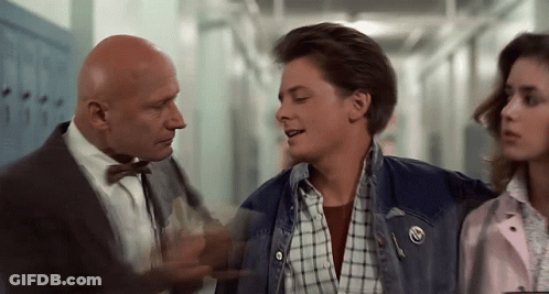A Man In A Suit And Bow Tie Is Talking To A Man In A Plaid Shirt And A Girl In A Pink Jacket . GIF