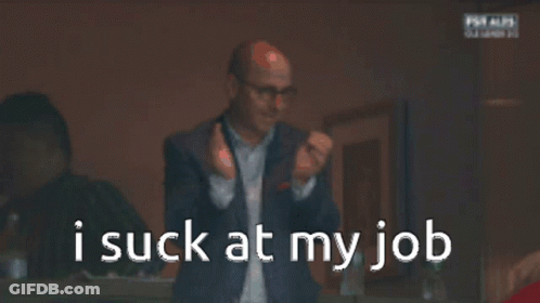 A Man In A Suit And Glasses Is Looking At His Phone With The Words I Suck At My Job Behind Him GIF