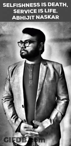 A Man In A Suit And Glasses Is Standing In Front Of A Sign That Says Selfishness Is Death Service Is Life GIF