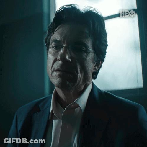 A Man In A Suit And Glasses Looks At The Camera With Hbo Written In The Corner GIF