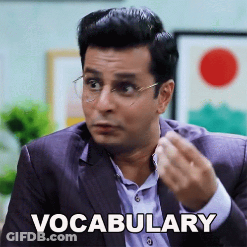 A Man In A Suit And Glasses Says Vocabulary With His Hand GIF