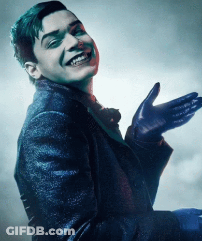 A Man In A Suit And Gloves Is Smiling With His Hand Outstretched GIF