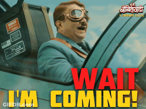 A Man In A Suit And Goggles Is Driving A Car With The Words Wait I 'M Coming In Red GIF