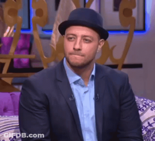 A Man In A Suit And Hat Is Sitting On A Couch With His Eyes Closed GIF