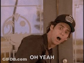 A Man In A Suit And Hat Is Standing In Front Of A Door With His Mouth Open And Says `` Oh Yeah '' . GIF