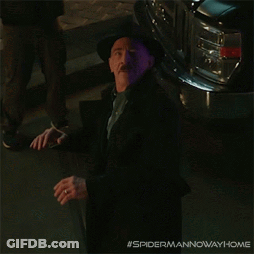 A Man In A Suit And Hat Is Standing In Front Of A Purple Car With The Hashtag #Spidermannowawayhome GIF