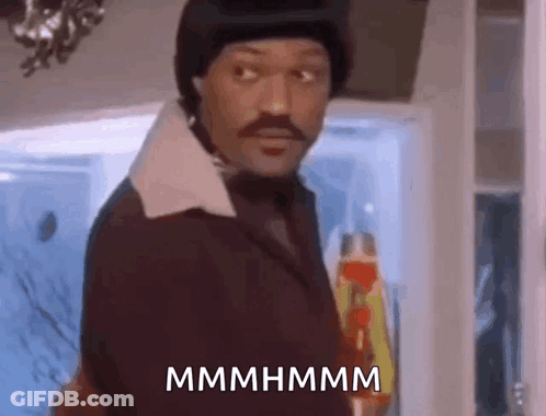 A Man In A Suit And Hat Is Standing In Front Of A Refrigerator And Holding A Bottle Of Ketchup . GIF