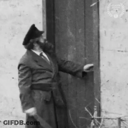 Man In Suit And Hat Standing Next To Door GIF